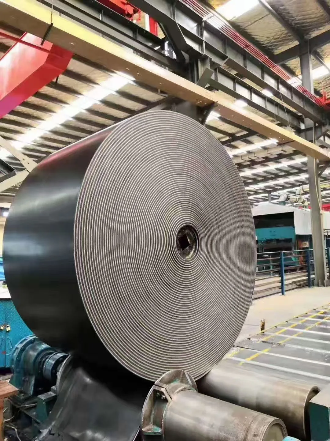 Large roll of black conveyor belting in a workshop