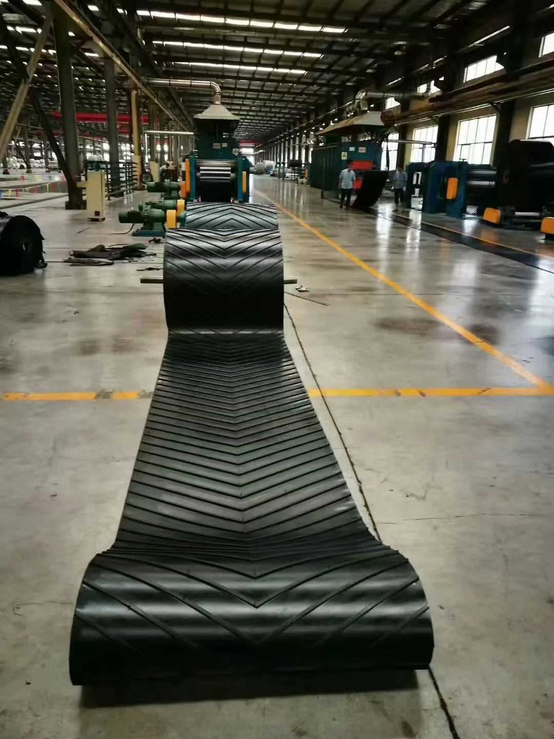Chevron-pattern conveyor belt laid out in a workshop