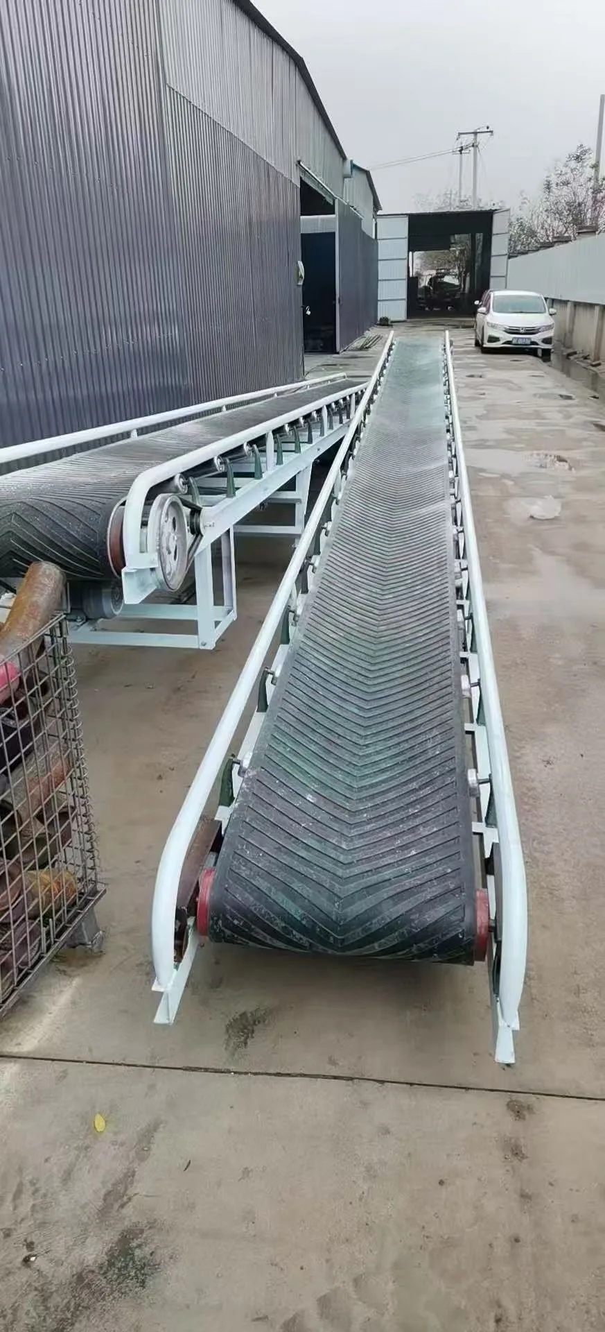 Inclined belt conveyor alongside a building